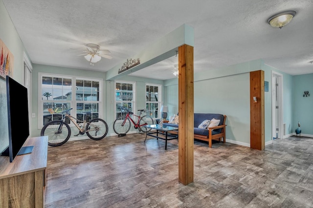 interior space with baseboards, ceiling fan, a textured ceiling, and a wealth of natural light
