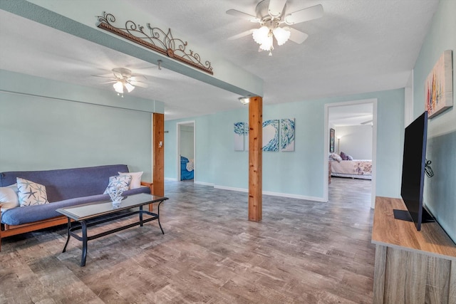 living room with baseboards, a ceiling fan, a textured ceiling, and wood finished floors