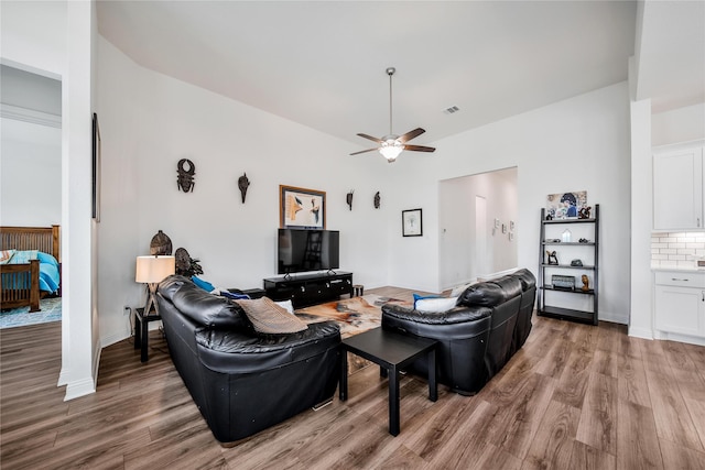living room featuring baseboards, a ceiling fan, light wood-type flooring, and visible vents