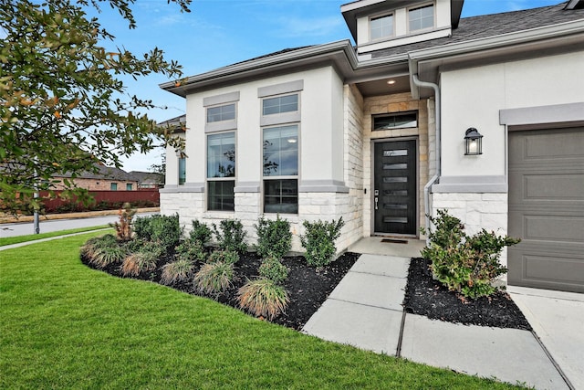 entrance to property with a lawn, a garage, stone siding, and stucco siding