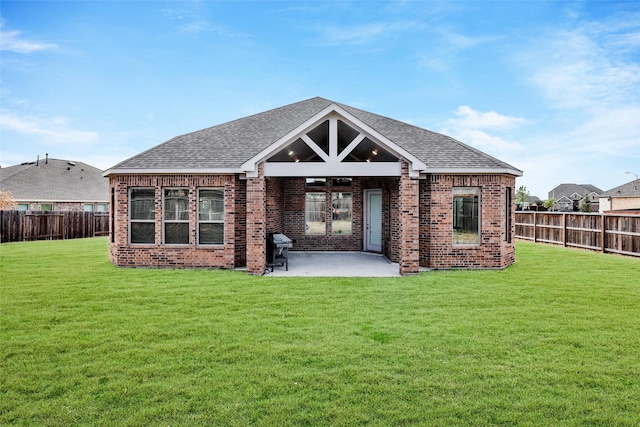 back of property featuring a fenced backyard, a patio area, roof with shingles, and brick siding