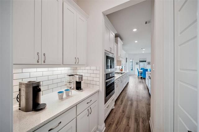 kitchen featuring decorative backsplash, dark wood-style flooring, visible vents, appliances with stainless steel finishes, and white cabinetry