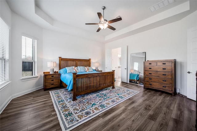bedroom featuring visible vents, baseboards, a raised ceiling, and wood finished floors