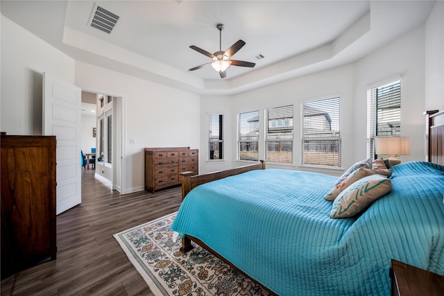 bedroom featuring baseboards, visible vents, dark wood-style floors, and a raised ceiling