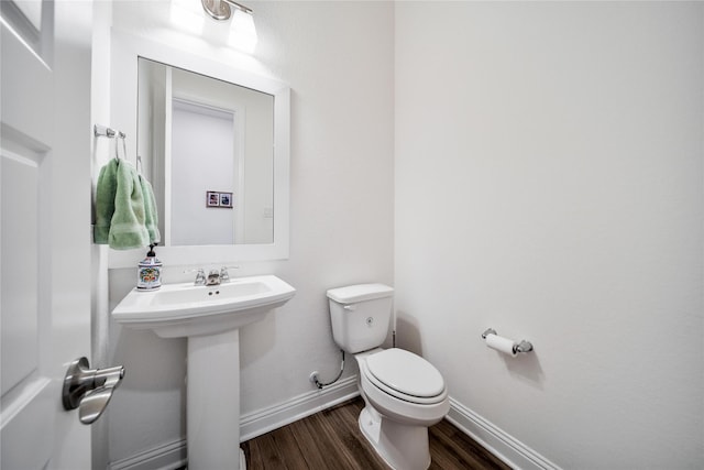 bathroom with toilet, baseboards, a sink, and wood finished floors