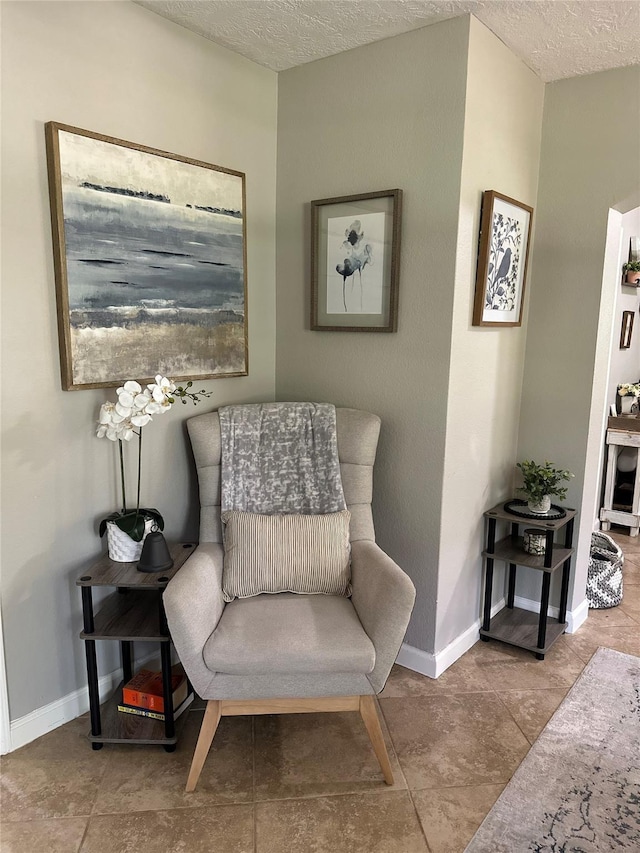 sitting room featuring a textured ceiling and baseboards