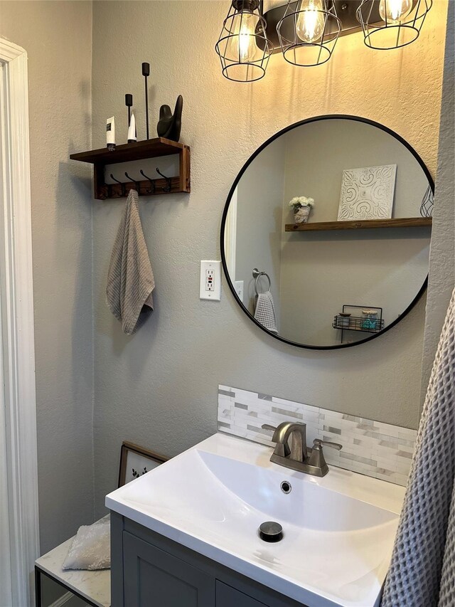 bathroom with an inviting chandelier, decorative backsplash, and vanity