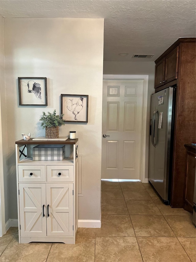 kitchen with visible vents, baseboards, dark brown cabinets, and stainless steel fridge with ice dispenser