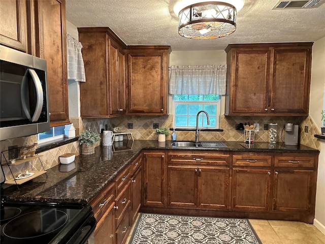 kitchen with a textured ceiling, stainless steel microwave, decorative backsplash, and a sink