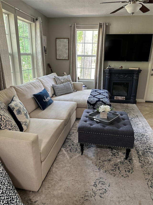 living area with a glass covered fireplace and a ceiling fan