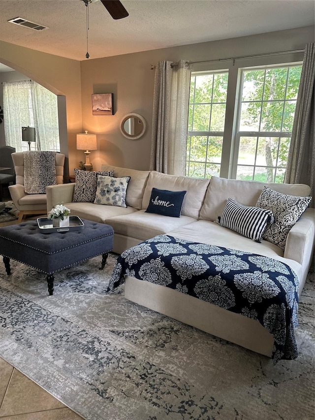 living area featuring a textured ceiling, ceiling fan, and visible vents