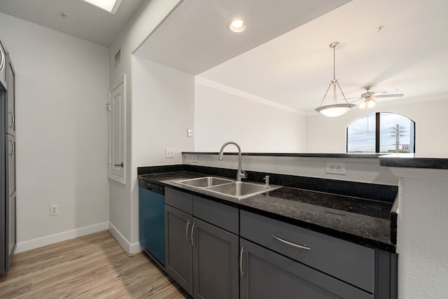 kitchen featuring crown molding, dark stone countertops, a sink, light wood finished floors, and dishwasher