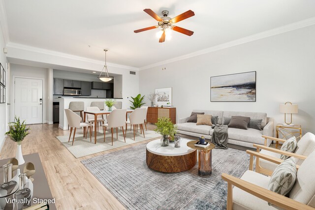 living room featuring crown molding, a ceiling fan, and light wood-style floors