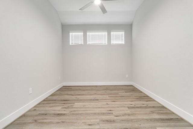 empty room featuring light wood-style floors, baseboards, vaulted ceiling, and a ceiling fan