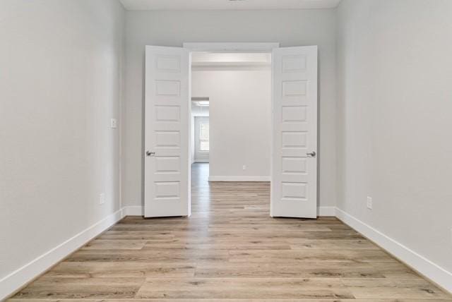spare room with light wood-type flooring and baseboards