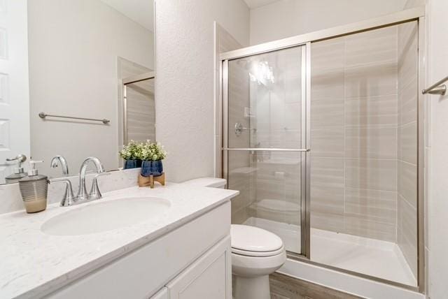full bathroom with toilet, a shower stall, wood finished floors, and vanity
