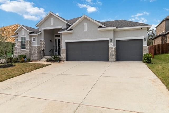 view of front of property featuring fence, an attached garage, stone siding, stucco siding, and concrete driveway
