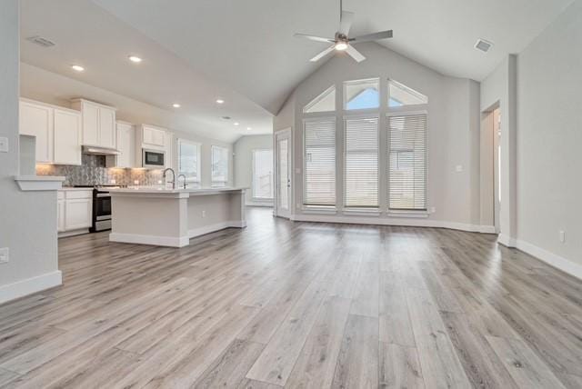 unfurnished living room with visible vents, a ceiling fan, light wood-style flooring, and a wealth of natural light
