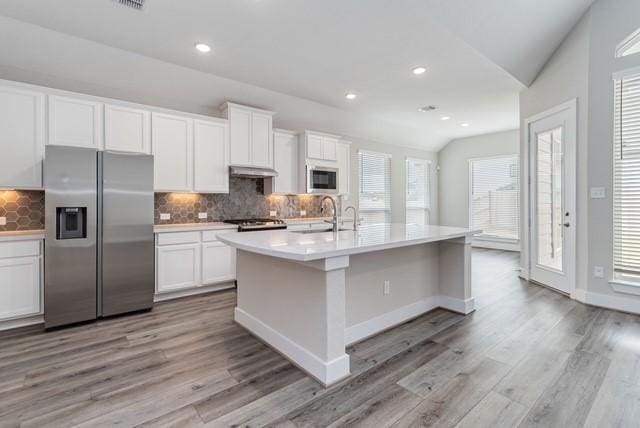 kitchen featuring a sink, built in microwave, stainless steel refrigerator with ice dispenser, and light wood-style flooring
