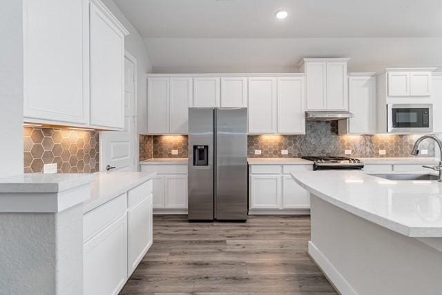 kitchen featuring built in microwave, a sink, stainless steel fridge with ice dispenser, light countertops, and under cabinet range hood