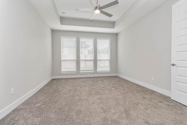 empty room with baseboards, carpet, a raised ceiling, and ceiling fan