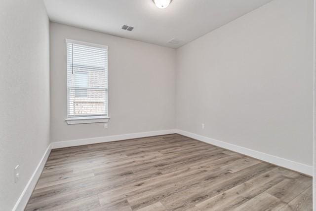 empty room with baseboards, wood finished floors, and visible vents