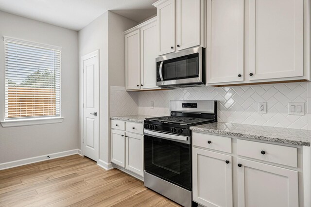 15686 Honey Cove Dr, Conroe, TX 77303 - kitchen featuring decorative backsplash, light wood-style flooring, white cabinetry, and stainless steel appliances