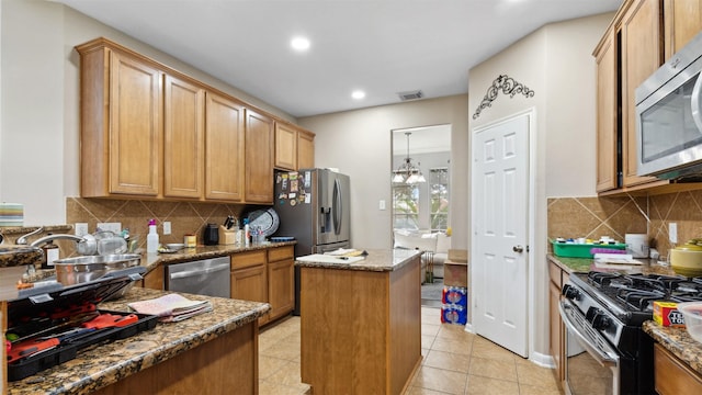 kitchen featuring a center island, dark stone counters, appliances with stainless steel finishes, and visible vents