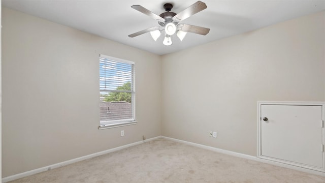 empty room with baseboards, a ceiling fan, and light colored carpet