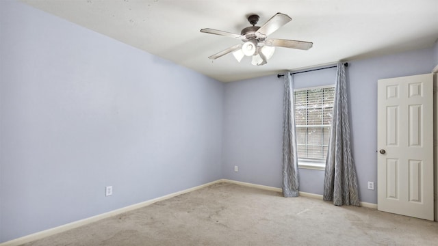 carpeted spare room featuring baseboards and a ceiling fan