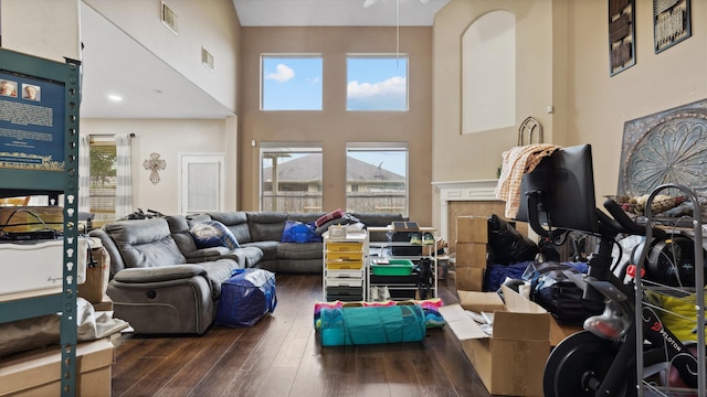 living room featuring a high ceiling, wood-type flooring, ceiling fan, and visible vents