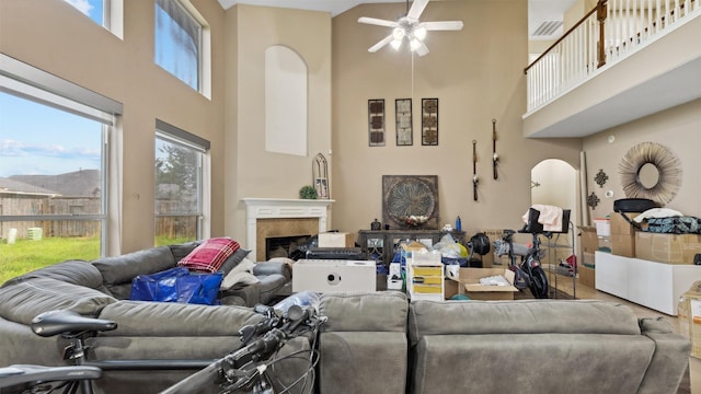 living area with a high ceiling, visible vents, ceiling fan, and a fireplace