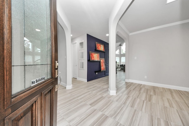 foyer with arched walkways, recessed lighting, baseboards, crown molding, and light tile patterned flooring
