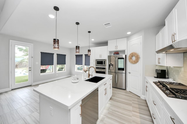 kitchen featuring a sink, stainless steel appliances, under cabinet range hood, light countertops, and recessed lighting