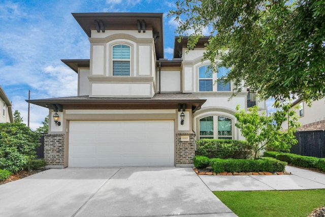 view of front of property featuring brick siding, stucco siding, an attached garage, driveway, and fence