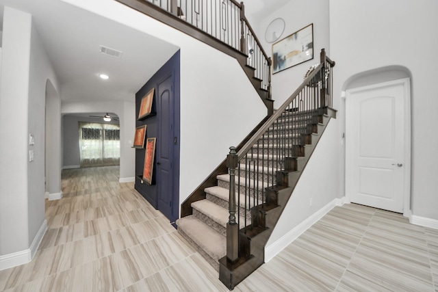 stairs with arched walkways, baseboards, tile patterned floors, and recessed lighting