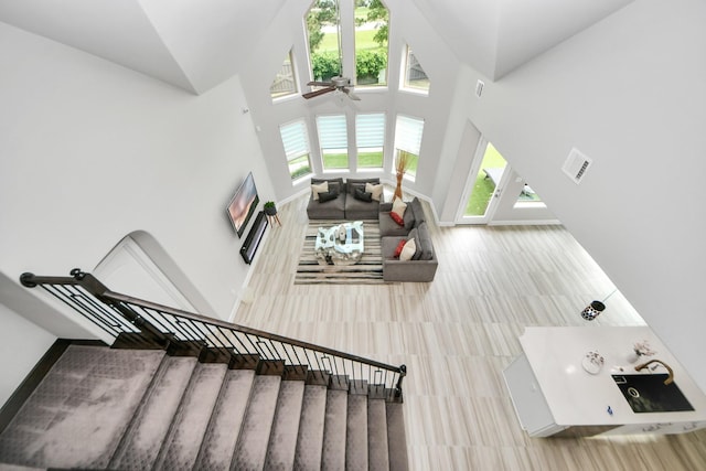 staircase with ceiling fan, high vaulted ceiling, and tile patterned flooring