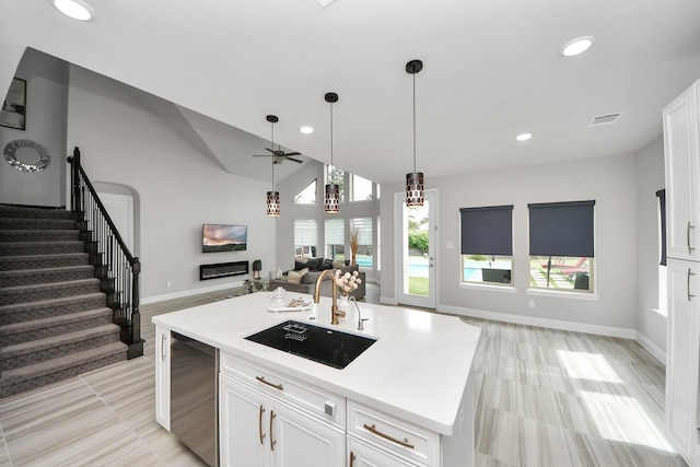 kitchen with a sink, open floor plan, ceiling fan, white cabinetry, and pendant lighting