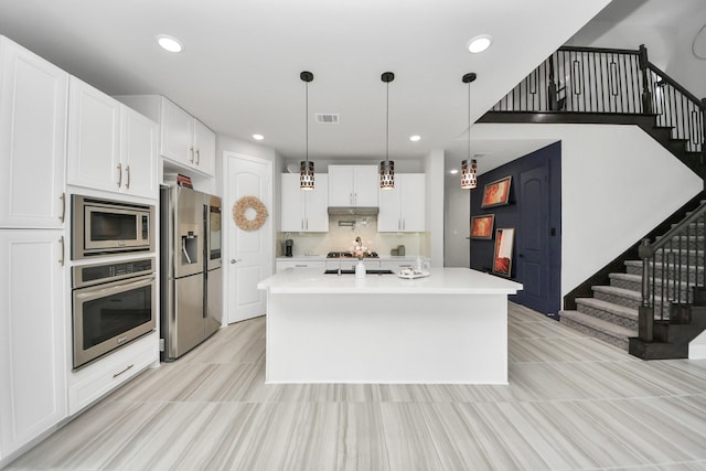 kitchen featuring stainless steel appliances, light countertops, white cabinets, recessed lighting, and hanging light fixtures
