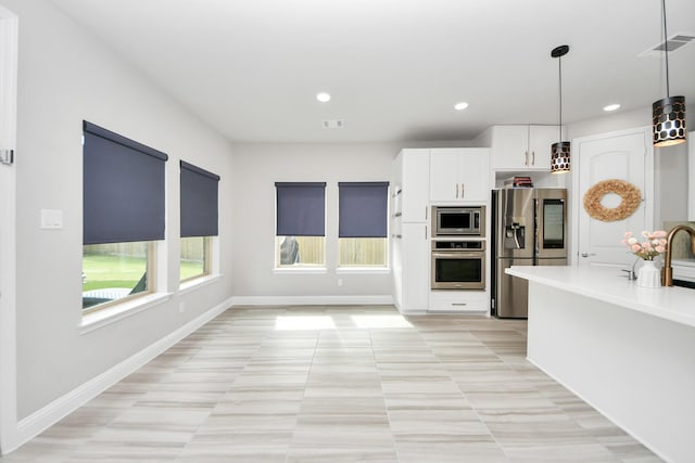kitchen featuring stainless steel appliances, white cabinets, pendant lighting, light countertops, and light tile patterned flooring