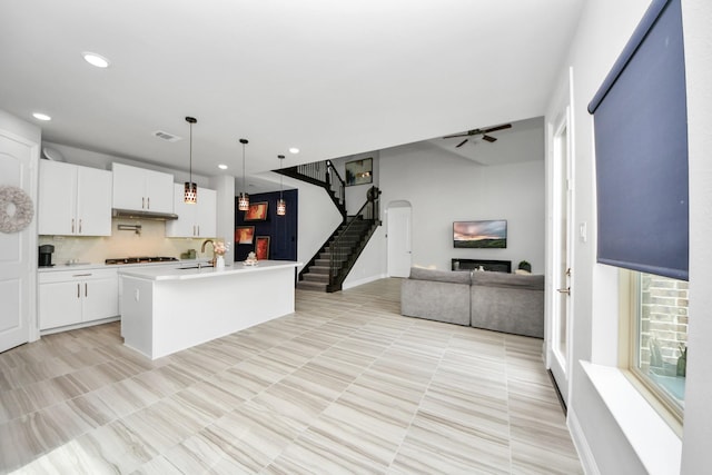 kitchen with gas stovetop, open floor plan, ceiling fan, light countertops, and a sink