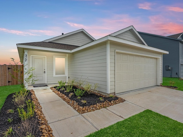 view of front of home featuring driveway, a shingled roof, an attached garage, and fence