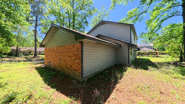 view of property exterior featuring brick siding and a yard