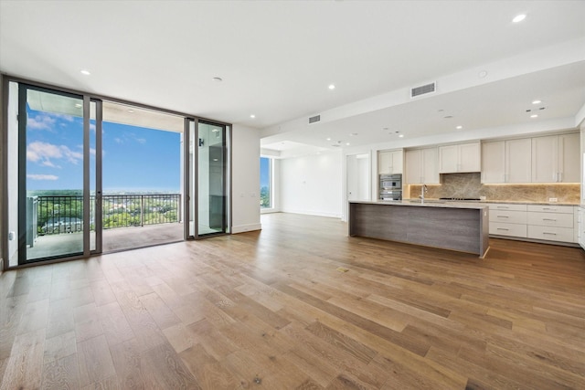 kitchen featuring a sink, open floor plan, floor to ceiling windows, tasteful backsplash, and visible vents