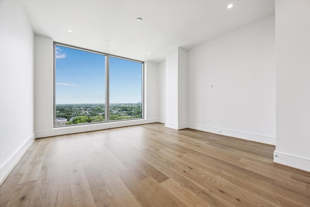 spare room with recessed lighting, baseboards, and wood finished floors