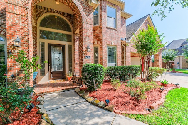 2402 Chesley Park Ct, Katy, TX 77494 - view of exterior entry featuring brick siding, driveway, a shingled roof, and a garage