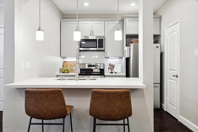 1201 Mcduffie St Unit 169, Houston, TX 77019 - kitchen with appliances with stainless steel finishes, a breakfast bar area, dark wood finished floors, light countertops, and hanging light fixtures