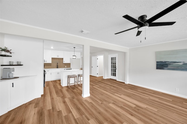 409 24th Ave N, Texas City, TX 77590 - unfurnished living room featuring a textured ceiling, light wood-style flooring, and ceiling fan