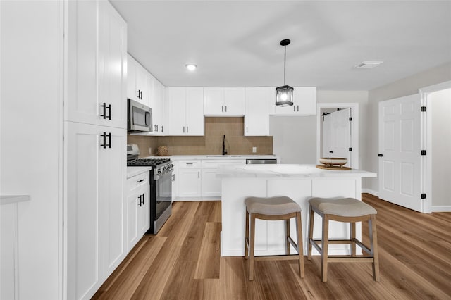 409 24th Ave N, Texas City, TX 77590 - kitchen featuring appliances with stainless steel finishes, a kitchen breakfast bar, wood finished floors, a kitchen island, and decorative backsplash