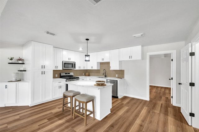 409 24th Ave N, Texas City, TX 77590 - kitchen with stainless steel appliances, white cabinetry, decorative backsplash, and light wood-style flooring